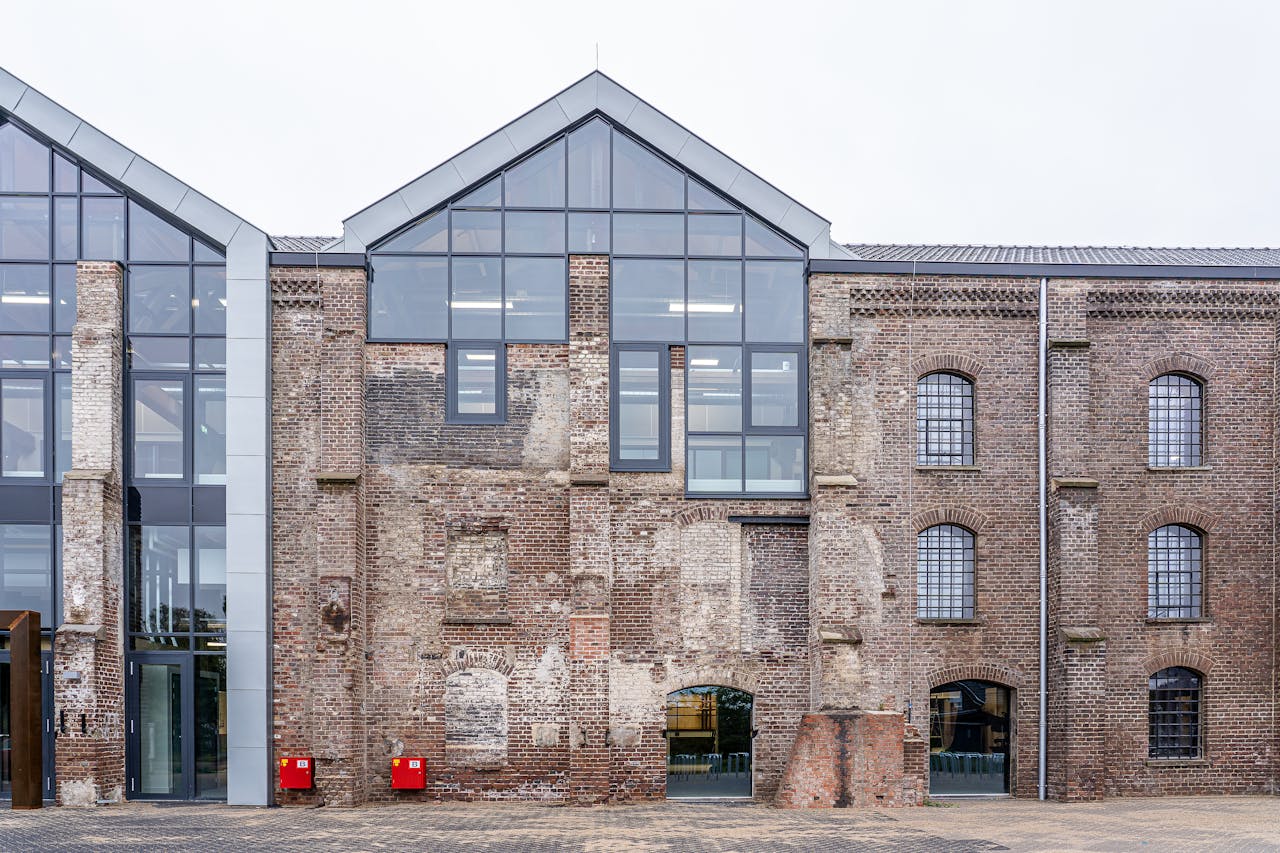 An architectural blend of modern glass and vintage brick in an urban setting.